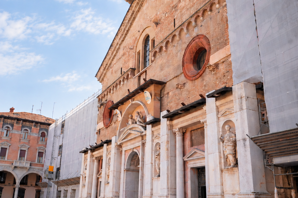 Facciata di una del Palazzo vescovile di Reggio Emilia in mattoni con ponteggi e teli protettivi installati ai lati dell'edificio.